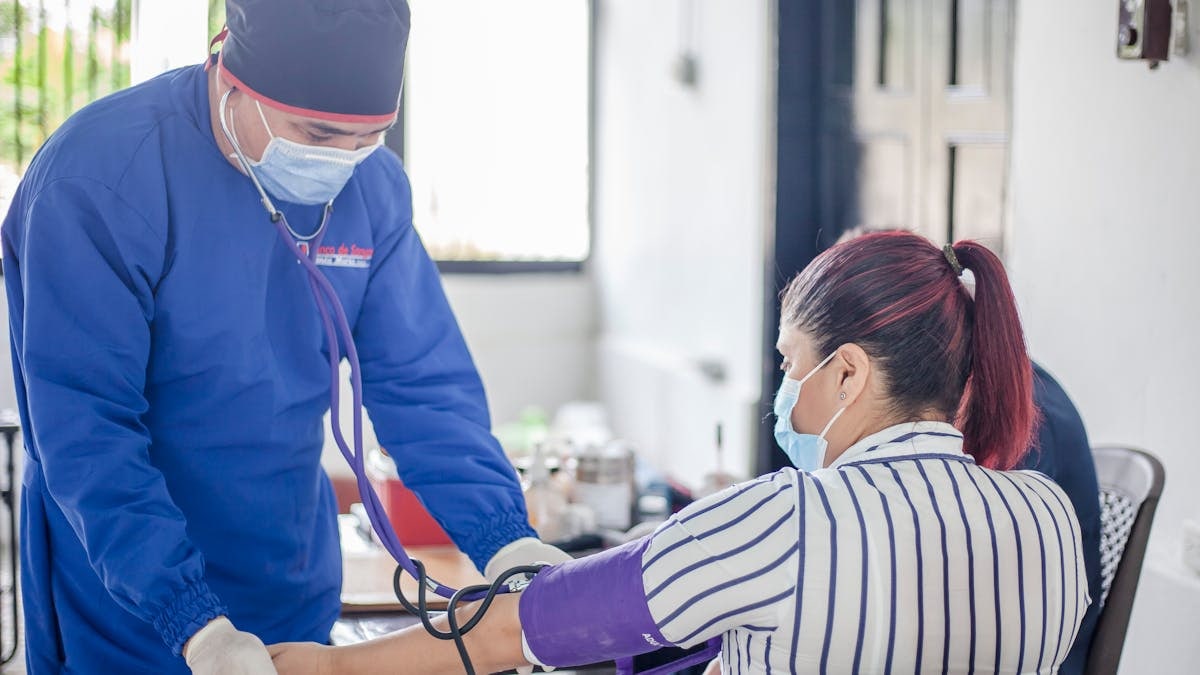 A nurse performs a blood pressure check on a patient in a healthcare setting, emphasizing safety and care.